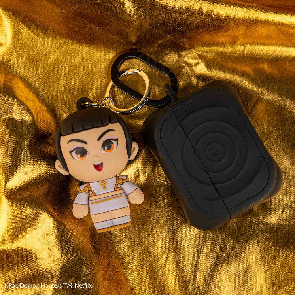 Officially licensed KPop Demon Hunters Zoey Gomee Keymate keyring attached to earbud case on gold fabric.