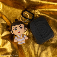 Officially licensed KPop Demon Hunters Zoey Gomee Keymate keyring attached to earbud case on gold fabric.