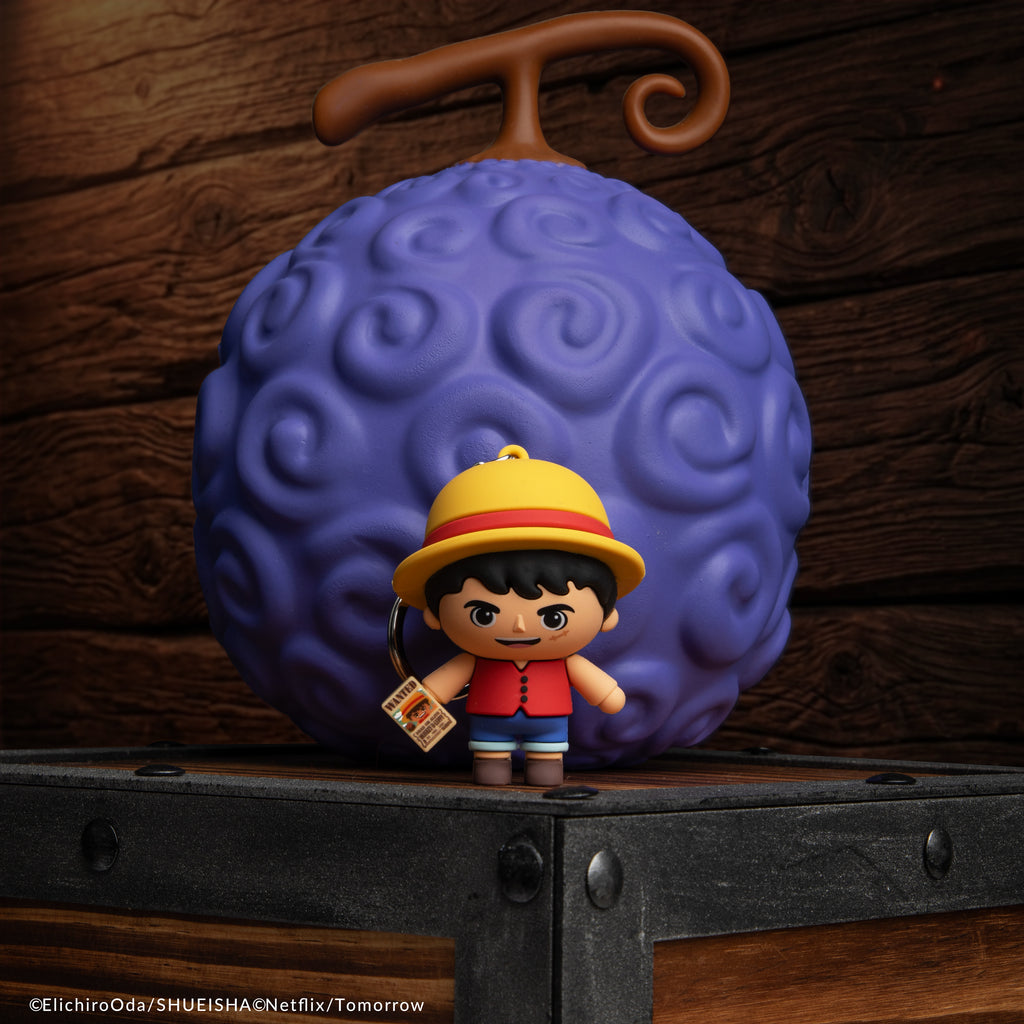 Officially licensed Netflix One Piece Monkey D Luffy Gomee Keymate keyring standing in front of a Devil Fruit Squishy by Cinereplicas.