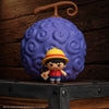 Officially licensed Netflix One Piece Monkey D Luffy Gomee Keymate keyring standing in front of a Devil Fruit Squishy by Cinereplicas.